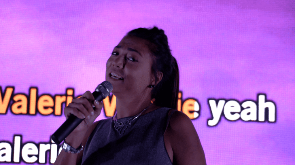 Une chanteuse au micro devant l'écran rose