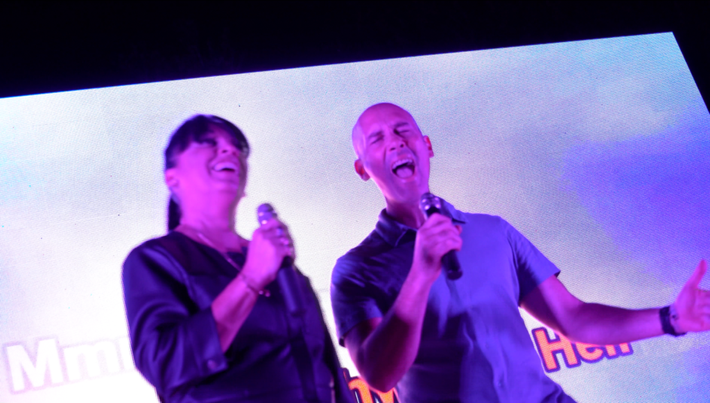 Une candidate et le chanteur du groupe rient en chantant