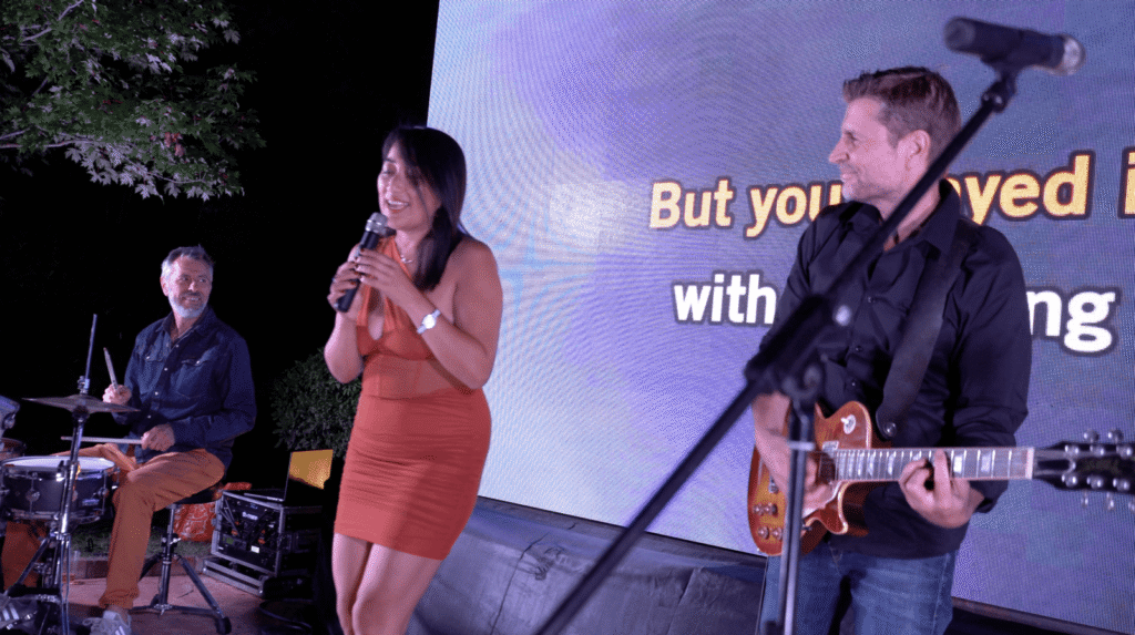Une chanteuse et le guitariste devant l'écran de paroles