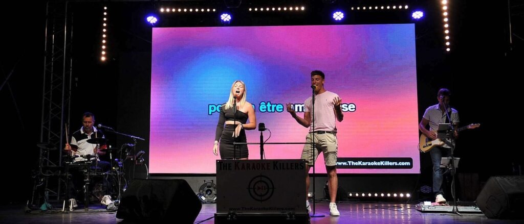 Un duo de spectateurs chante devant l'écran, le guitariste les accompagne
