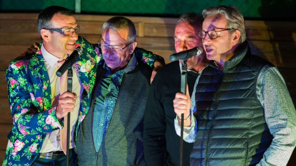 Quatre hommes chantent ensemble au micro pendant la soirée