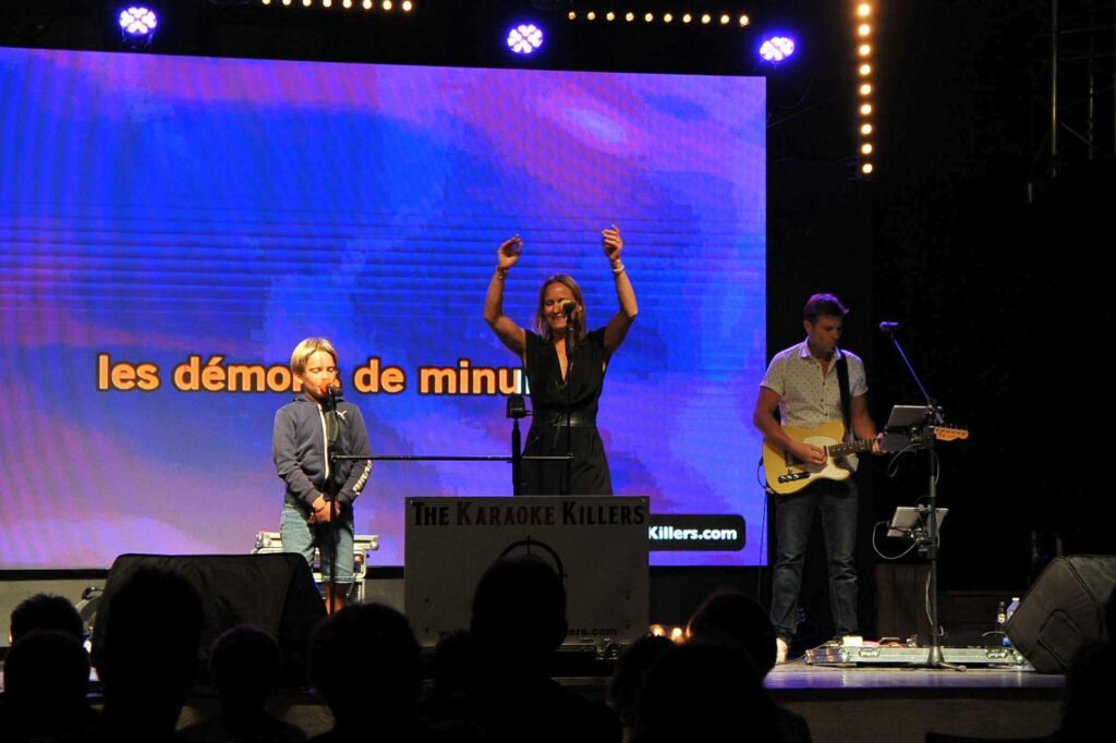 Een toeschouwster steekt haar armen omhoog terwijl ze zingt, begeleid door de gitarist