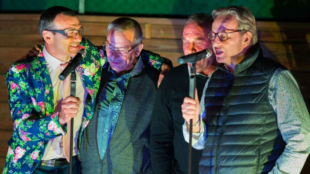 Vier mannen zingen samen in de microfoon tijdens de avond