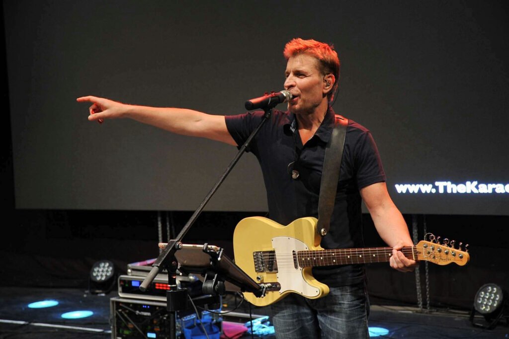 De zanger-gitarist van de band wijst vanaf het podium naar het publiek