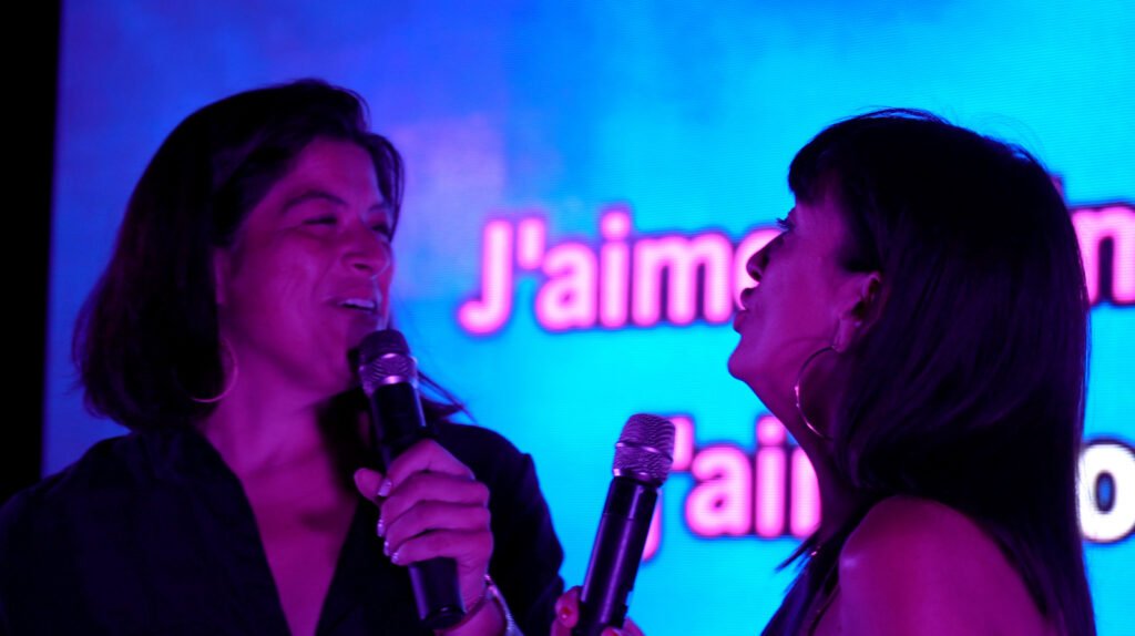 Deux candidats chantent en duo devant l'écran de paroles