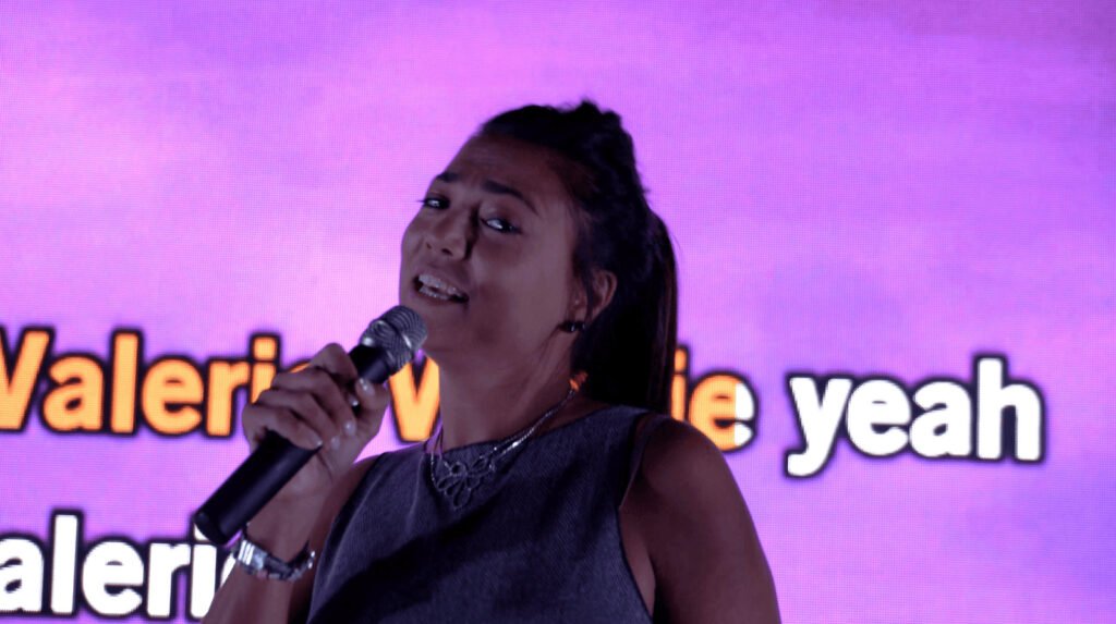 A singer at the microphone in front of the pink screen