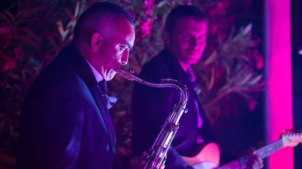 The saxophonist plays under red lighting