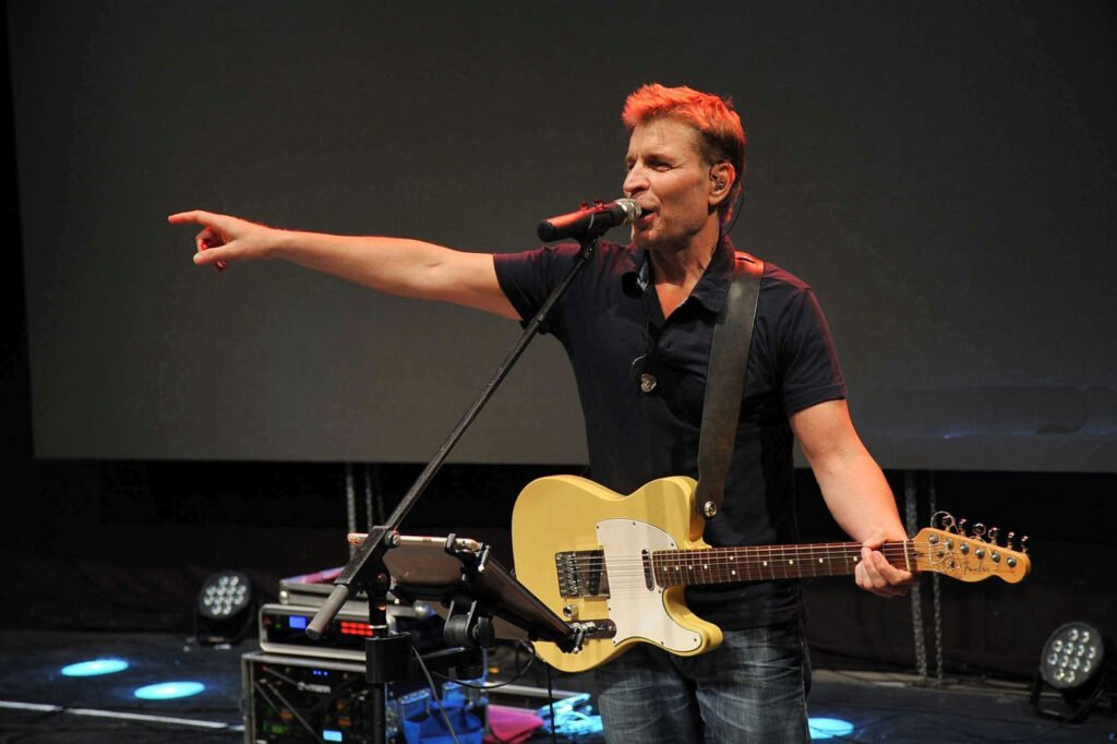 The singer-guitarist points to the audience from the stage