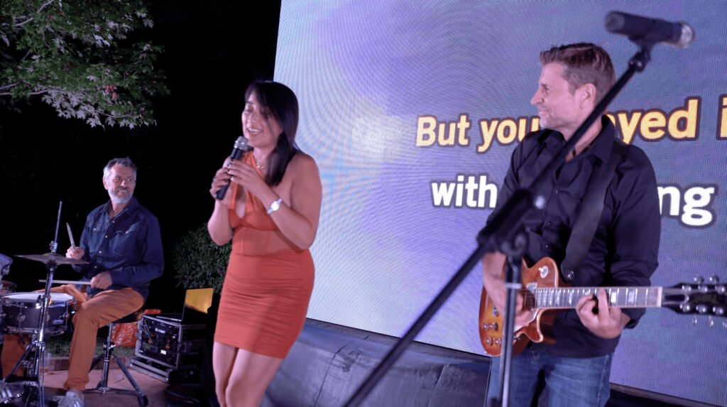 A singer and the guitarist in front of the lyrics screen